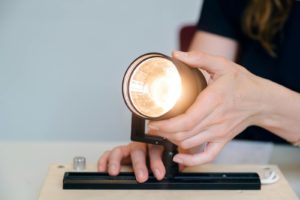 A female engineer testing a light fixture prototype in an office setting, showcasing innovation.